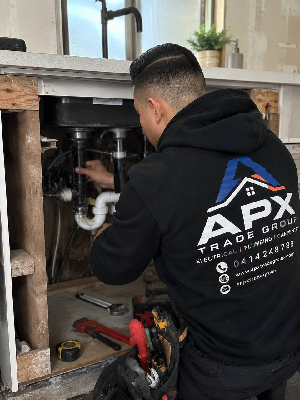 Licensed plumber repairing pipes under a sink